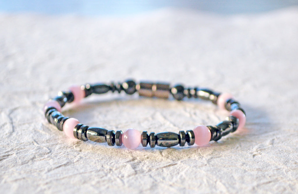 Magnetic bracelet is handcrafted with black high power magnetic hematite beads and pink cat's eye fiber optic beads. It is secured with a strong and easy-to-use magnetic clasp.