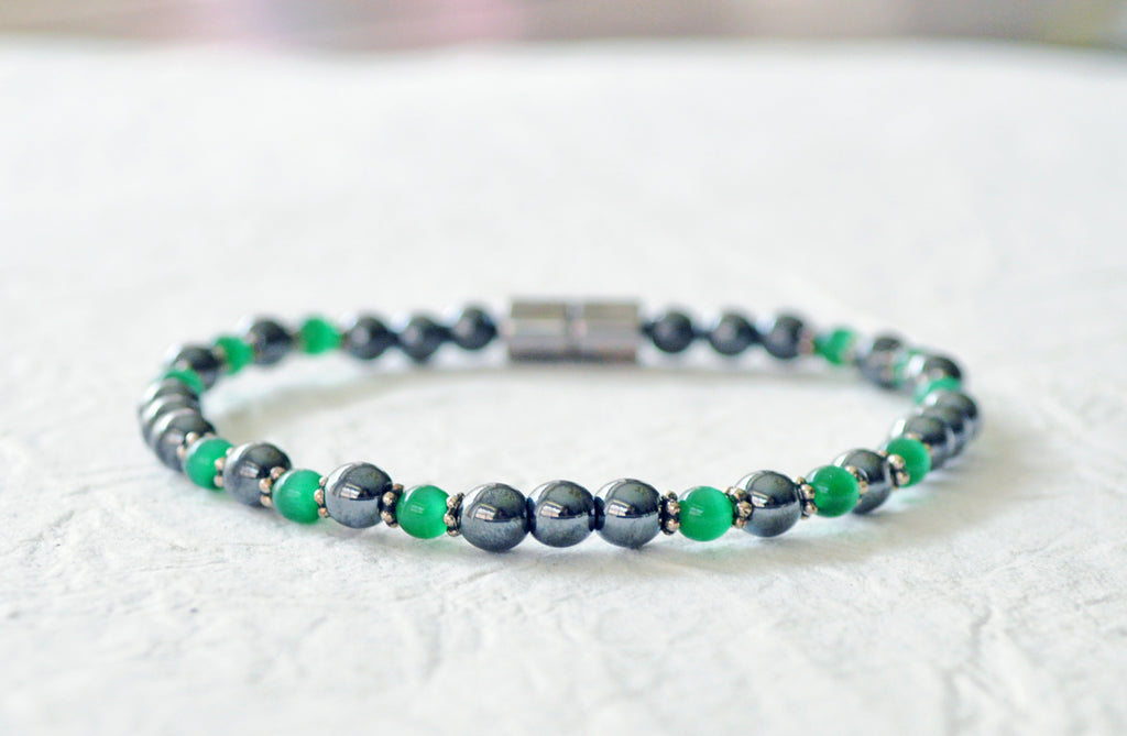 Magnetic bracelet handcrafted with black high power magnetic hematite beads, green cat's eye beads, and antique silver spacer beads. It is secured with a strong and easy-to-use magnetic clasp.