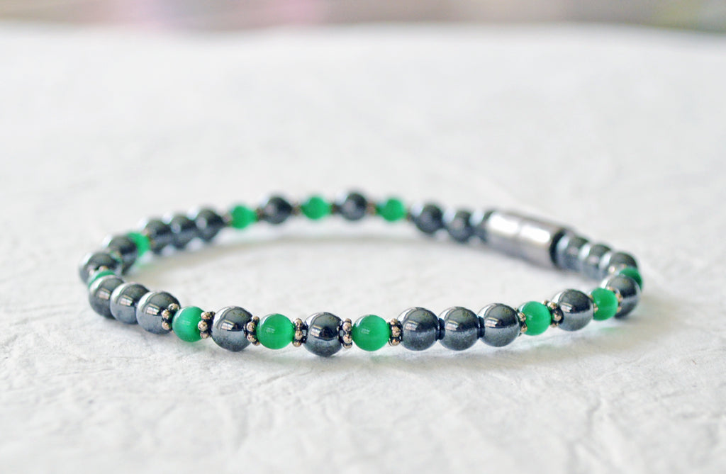 Magnetic bracelet handcrafted with black high power magnetic hematite beads, green cat's eye beads, and antique silver spacer beads. It is secured with a strong and easy-to-use magnetic clasp.