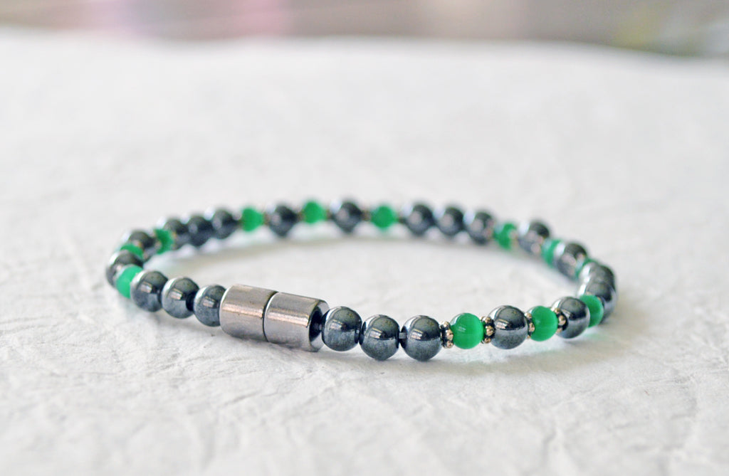 Magnetic bracelet handcrafted with black high power magnetic hematite beads, green cat's eye beads, and antique silver spacer beads. It is secured with a strong and easy-to-use magnetic clasp.