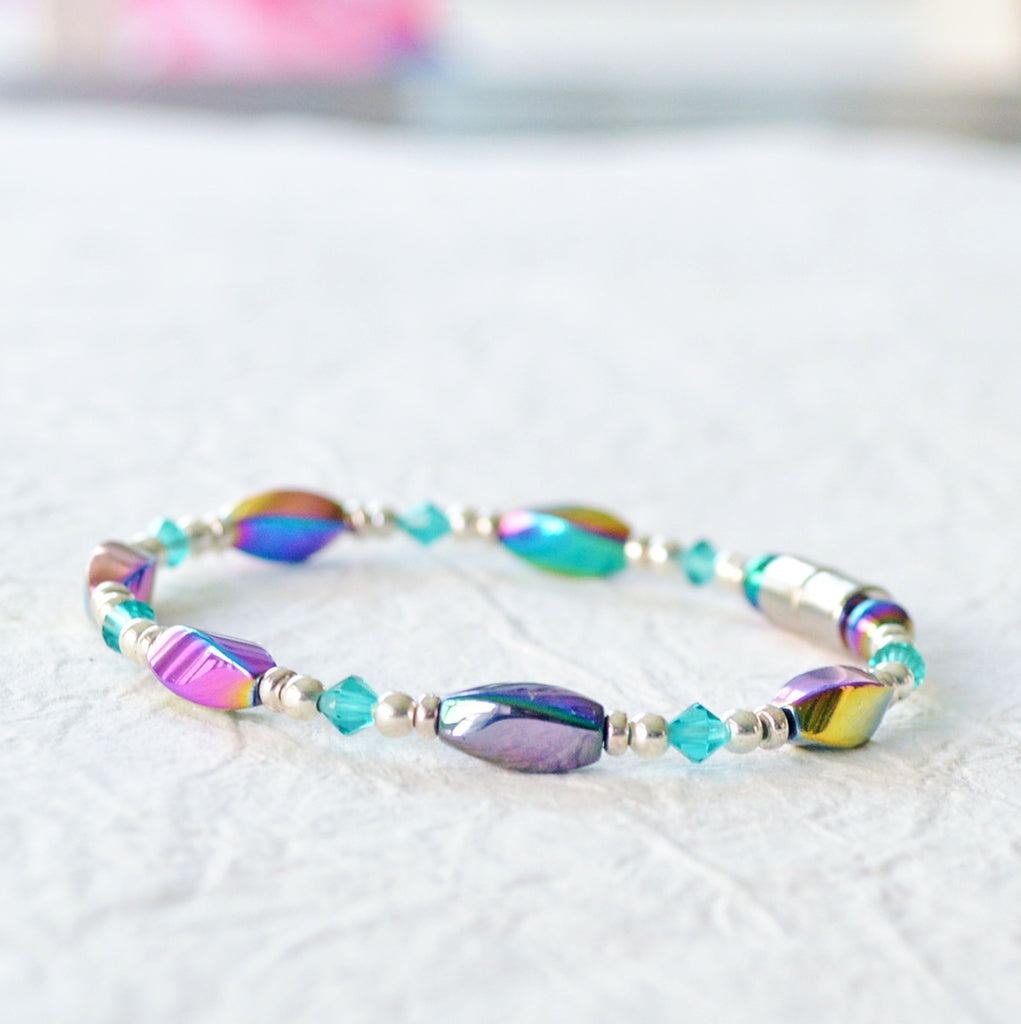 Magnetic bracelet handcrafted with iridescent rainbow hematite magnetic beads with bicone shaped teal crystal beads and silver spacer beads. Secured with a strong magnetic clasp. Wears well as a magnetic bracelet or a magnetic ankle bracelet.