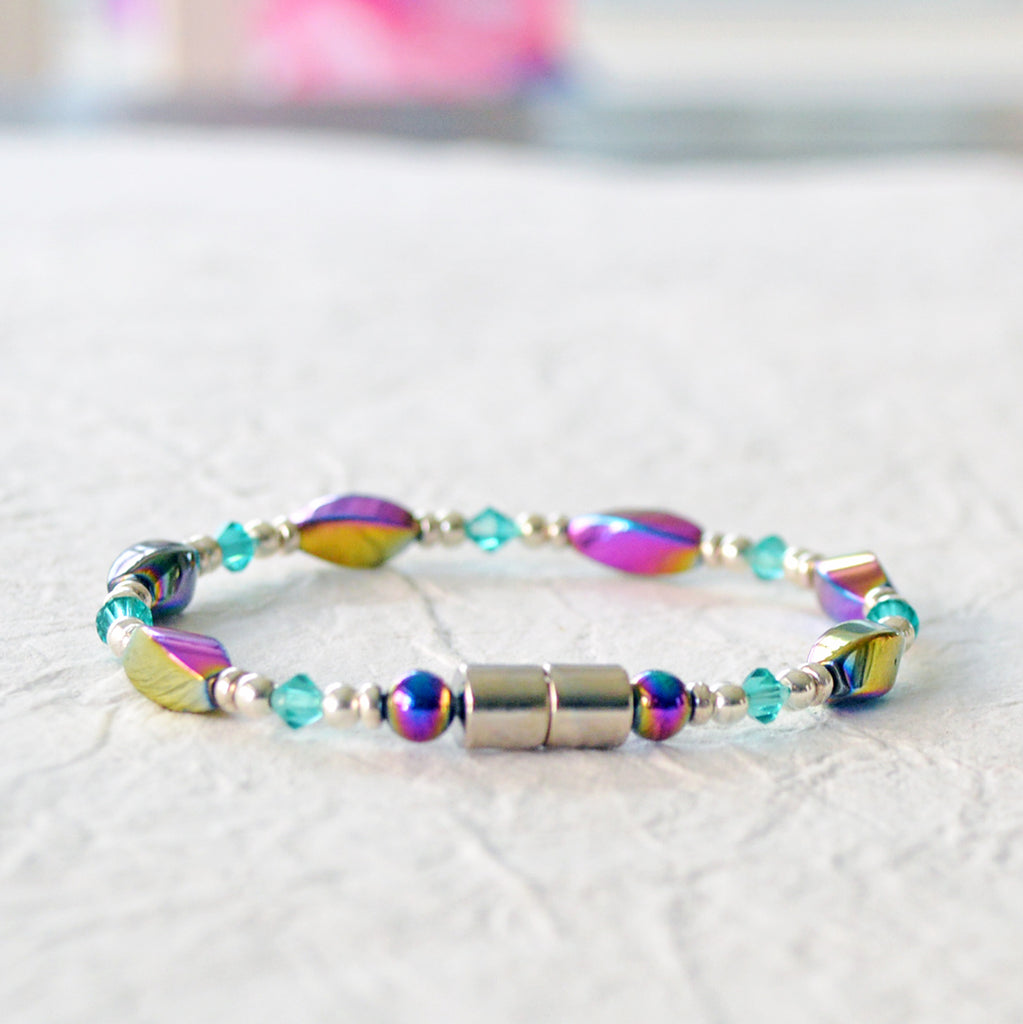 Magnetic bracelet handcrafted with iridescent rainbow hematite magnetic beads with bicone shaped teal crystal beads and silver spacer beads. Secured with a strong magnetic clasp. Wears well as a magnetic bracelet or a magnetic ankle bracelet.