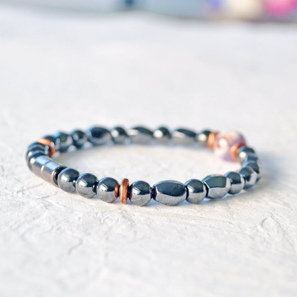 Magnetic Hematite bracelet handcrafted with black magnetic hematite beads and antique copper spacer beads. In the center is a single flower amethyst gemstone bead. Secured with a strong magnetic clasp.