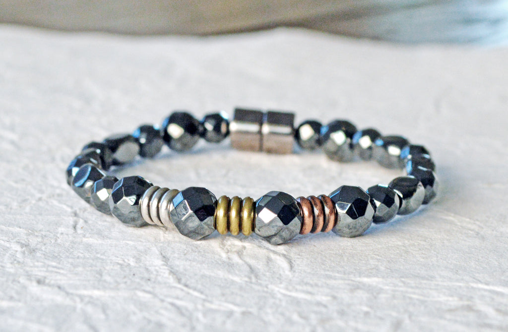 Magnetic therapy bracelet handcrafted with black high power magnetic hematite beads. In the center of the bracelet are three metal beads - one in copper, one brass, and one silver. Magnetic bracelet is secured with a strong and easy-to-use magnetic clasp.