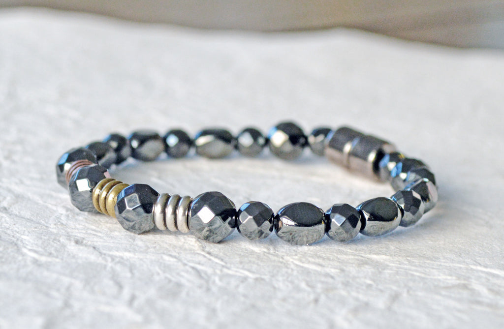 Magnetic therapy bracelet handcrafted with black high power magnetic hematite beads. In the center of the bracelet are three metal beads - one in copper, one brass, and one silver. Magnetic bracelet is secured with a strong and easy-to-use magnetic clasp.